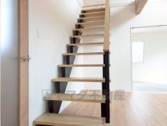 木の温もりとブラックフレームが調和したスケルトン階段。光と視線を遮らず、空間全体に開放感をもたらします。デザイン性と機能性を兼ね備えた印象的なアクセントです。