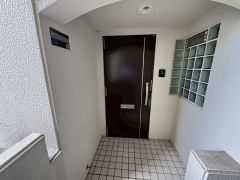 白を基調とした外壁に、ダークブラウンの玄関ドアが映えるアプローチ。ガラスブロックがアクセントでおしゃれ。