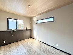 木目調の天井と落ち着いた色合いのアクセントクロスがおしゃれな洋室