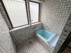 大きな窓があり換気良好な浴室。爽やかな水色の浴槽と全面タイル張りのレトロな空間が、日々の疲れを優しく癒します。
